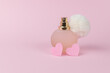 Women's perfume in an original bottle and two pink hearts on a pink background.