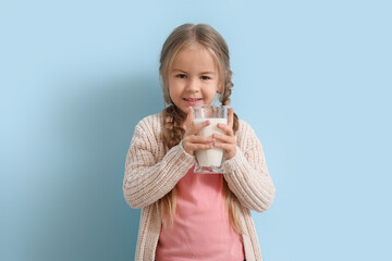 Wall Mural - Cute little girl with glass of tasty milk on blue background