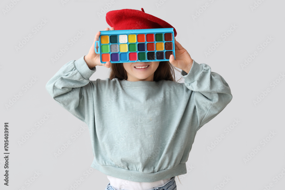 Cute little artist with paints on light background. Opposite Day celebration