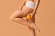 © Pixel-Shot - Beautiful young woman with cellulite problem and orange on brown background