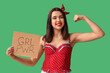 Beautiful young happy pin-up woman holding paper sheet with text GIRL POWER and showing muscles on green background