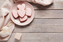 Plate with tasty heart shaped cookies, decor and gift box on grey wooden background. Valentine's Day celebration