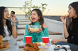 © Prathankarnpap - Group of Asian millennial friends enjoying dinner party at rooftop during sunset.