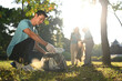 © Prathankarnpap - Smiling Asian male volunteer and his colleagues picking up plastic trash in public park