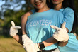 © Prathankarnpap - Cropped shot of two smiling young women volunteers pointing fingers at lettering on blue t-shirts