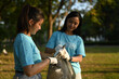 © Prathankarnpap - Two young female volunteers with garbage bag cleaning up the forest. Charity and ecology concept
