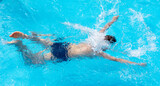 Fototapeta Łazienka - A teenage boy swims in the blue water of a pool
