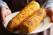 Caucasian male hands holds plate with grilled sweetcorn