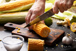 Female hands cut sweetcorn cobs on cutting board low angle view
