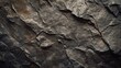 Textured stone background created by a dark brown, rough mountain surface with prominent cracks. Substantial space available for design.

