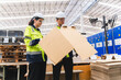 Professional worker team in safety uniform, supervisor inspector in packaging stock order at cardboard factory warehouse, piles of stacking paper manufacture, recycling industrial production