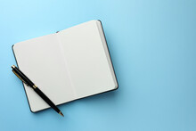 Open Notebook With Blank Pages And Pen On Light Blue Background, Top View. Space For Text