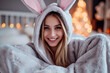 happy smiling woman sitting at home and wearing a easter bunny costume 