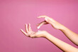 Beautiful woman hands touching cream isolated over pink background
