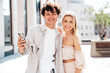 © halayalex - Young smiling beautiful woman and her handsome boyfriend in casual summer clothes. Happy cheerful family. Female having fun. Couple posing in street. Hold smartphone, use phone apps, look at screen