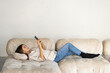 © F8  \ Suport Ukraine - Close up of a woman using a smart phone lying on a sofa in the living room at home with a cozy background