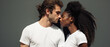 © Synthetica - Young multicultural couple in white t-shirts looking at each other isolated on grey.