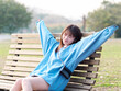 Beautiful young Chinese woman posing in sunny summer forest, wearing blue loose oversized top and miniskirt with small shoulder bag. Emotions, people, beauty, youth and lifestyle portrait.