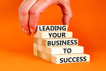 Wall Mural - Leading your business to success symbol. Concept words Leading your business to success on wooden blocks. Beautiful orange table orange background. Leading your business to success concept. Copy space