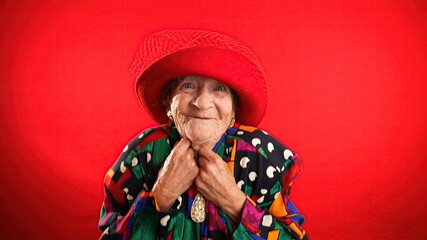 Wall Mural - Portrait of funny elderly senior old woman with no teeth and wrinkled skin looks at camera gives great idea gesture showing explosion of thinking posing isolated on red background