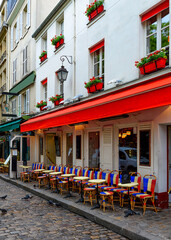 Wall Mural - Cozy street with tables of cafe in quarter Montmartre in Paris, France. Architecture and landmarks of Paris. Postcard of Paris