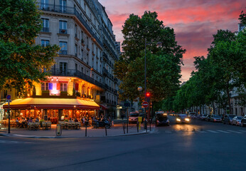 Wall Mural - Cozy street with tables of cafe in Paris, France. Night cityscape of Paris. Architecture and landmarks of Paris.