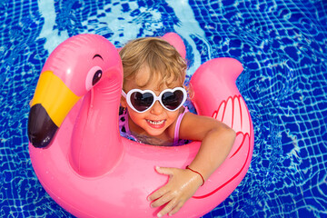 Poster - A child swims in a pool in a circle of flamingos. Selective focus.