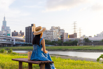 Wall Mural - Woman sit beside the river park in Taipei city in the evening