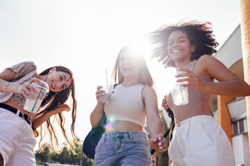 Wall Mural - Close up of three teenage girls in casual clothes drinking tasty lemonade on the go