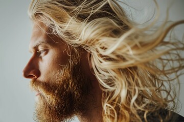 Wall Mural - Profile portrait of handsome Caucasian bearded blonde man contented expression and healthy long hair