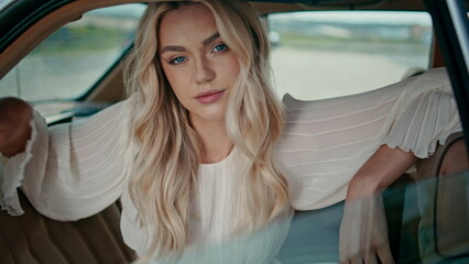 Gorgeous woman posing automobile back seat looking camera confidently close up.