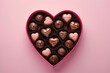 Pink heart-shaped box with delicious chocolates on a pink background. St Valentines Day concept. Copy space.