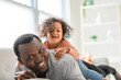 © Louis-Paul Photo - American father with little girl at home lay on sofa