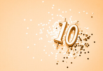 10 years celebration festive background made with golden candles in the form of number Ten lying on sparkles. Universal holiday banner with copy space.