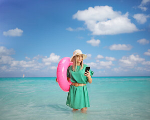 Canvas Print - Young woman with a swimming ring browsing on a smartphone