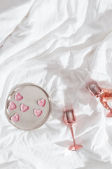 Wall Mural - Pink colored shiny champagne glass in woman hand, burning candles as hearts on bed cloth. Minimal lifestyle aesthetic photo, Valentine's Day, romance relationship, love concept, romance evening