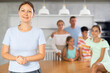 © JackF - Confident smiling mom poses with arms crossed on chest in cozy kitchen, large family with four children and husband are standing behind
