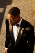 from above elegant African American male wearing expensive tuxedo walking along street and looking down