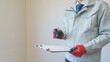 マンションの壁紙を点検する作業服の男性｜リフォーム調査・見積り　イメージ