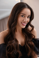 Wall Mural - Portrait of smiling woman with curly hair on blurred background