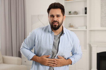 Canvas Print - Young man suffering from stomach pain indoors