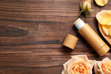 Fototapeta  - Lip balm and roses on wooden background, flat lay. Space for text