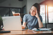 © Satori Studio - Businesswoman is serious at work causing headaches and stressed out with documents with a laptop at the office