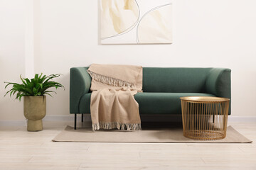 Sticker - Stylish living room interior with comfortable sofa, blanket, houseplant and side table