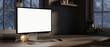 © bongkarn - A computer desk in a modern room at night, a white-screen computer mockup on a hardwood desk.