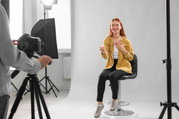 Poster - Casting call. Woman performing while camera operator filming her against light grey background in studio