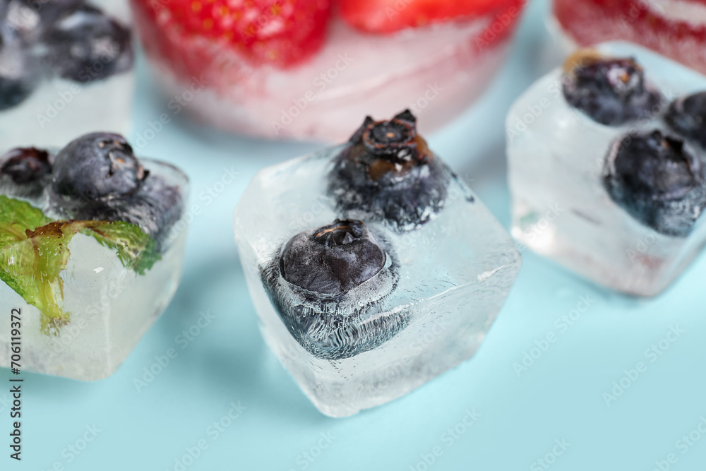 Fresh blueberry frozen in ice cubes on blue background, closeup