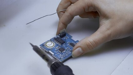 Poster - Close up of engineer does computer motherboard soldering. Creative. Painstaking work of soldering a chip.