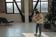 © teksomolika - With sunlight flooding in, an energetic young woman enjoys a virtual reality experience in her apartment.