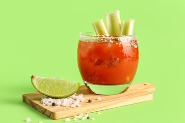 Fototapeta board with glass of bloody mary and celery on green background